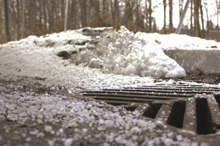 Winter storm drain with road salt scattered nearby